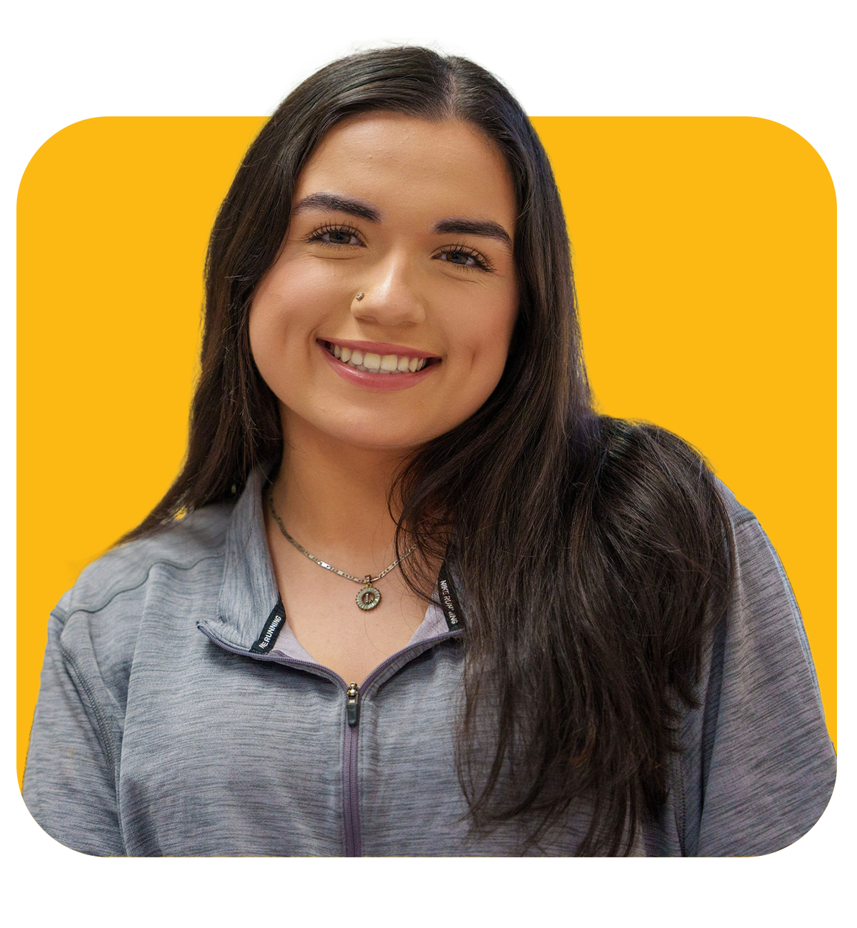 a female student wearing a grey sweater and a silver necklace, smiling at the camera