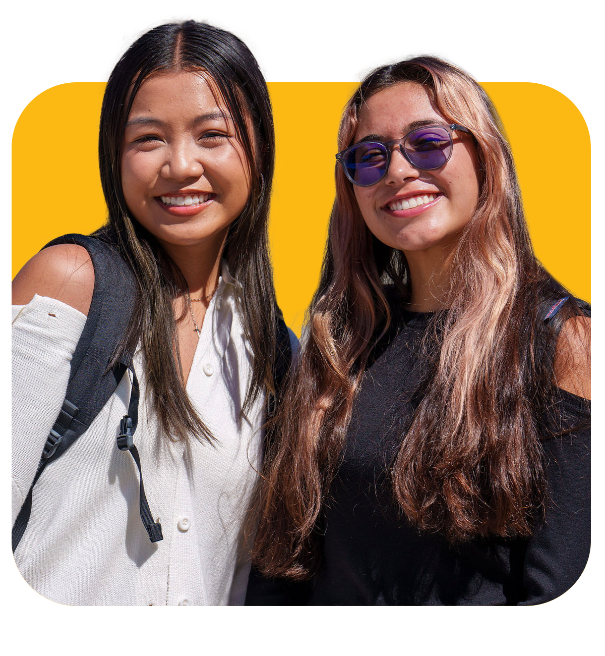2 female students, both smiling at the camera, the one on the left is wearing a white shirt and backpack and the one on the right is wearing a black shirt and black sunglasses