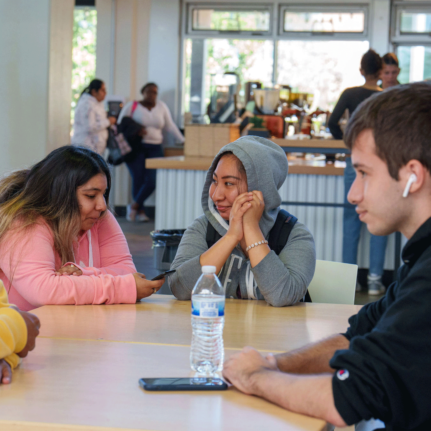 Group of college students chatting around a table in a campus café.