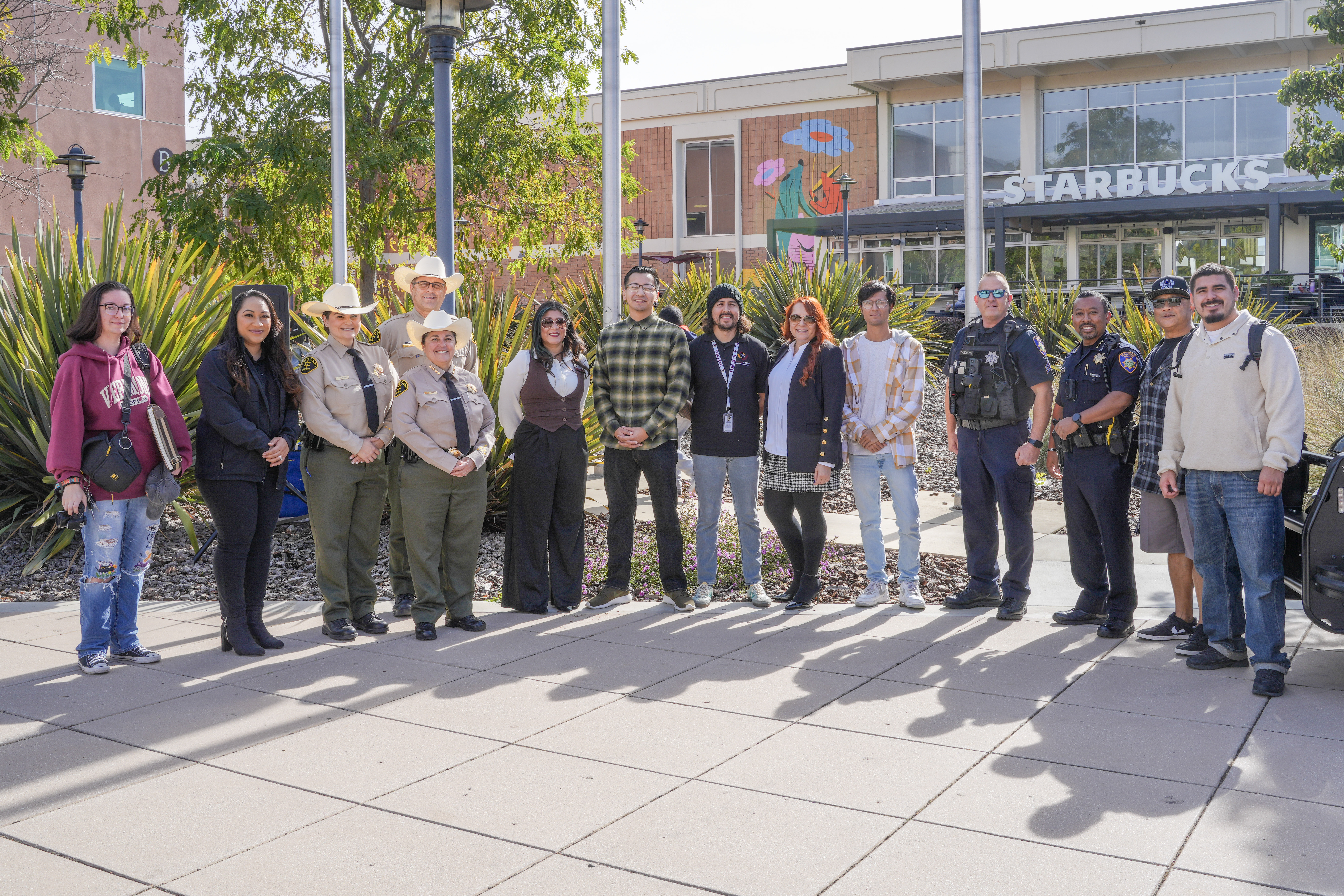 Group of law enforcement officers, students, and community members pose during an outreach event.